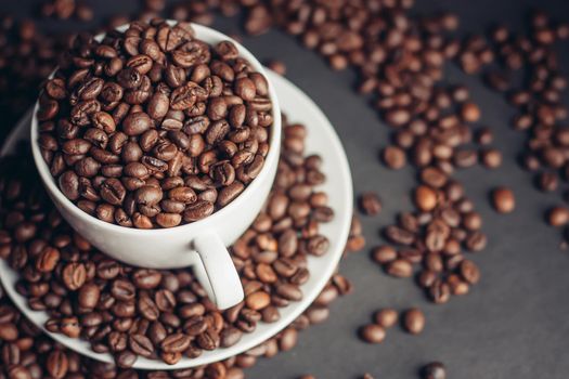 a cup with coffee beans stands on a saucer on a gray background close-up. High quality photo