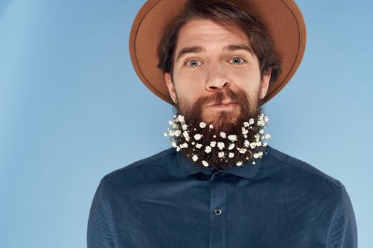 emotional bearded man flowers in hair hat shirts close-up. High quality photo