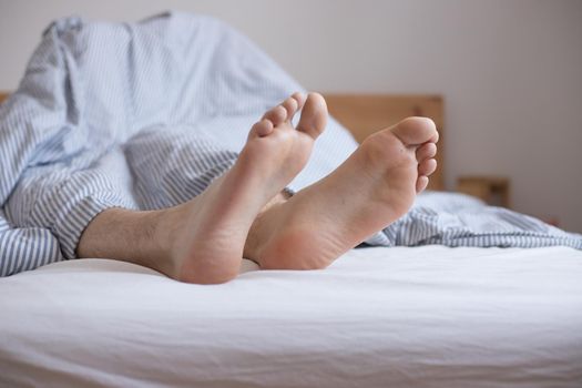 Close up uncovered female adult feet sleeping in bed, morning