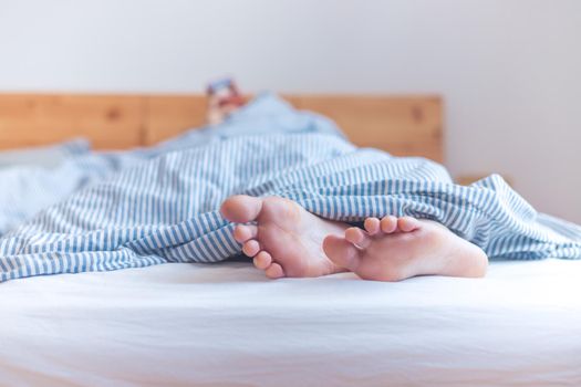 Close up a couples uncovered feet sleeping in bed, morning