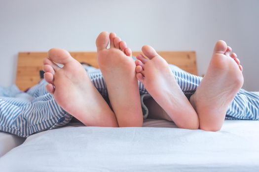 Close up a couples uncovered feet sleeping in bed, morning