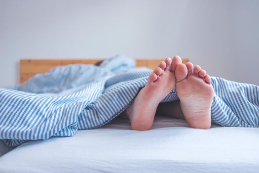 Close up uncovered female adult feet sleeping in bed, morning
