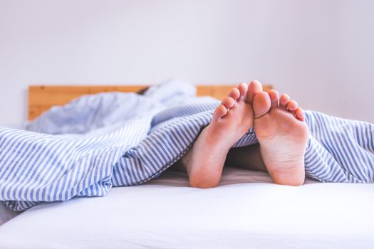Close up uncovered female adult feet sleeping in bed, morning
