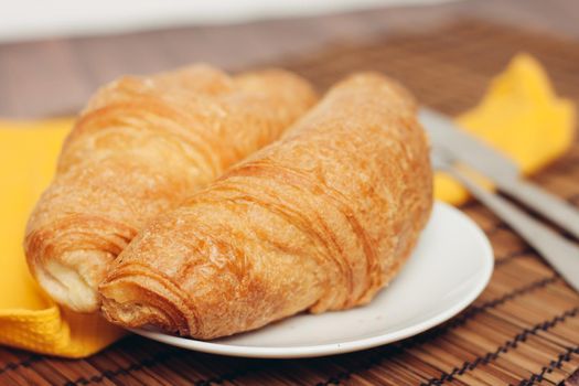 croissants saucer on the table fork with a knife fresh pastries dessert morning. High quality photo