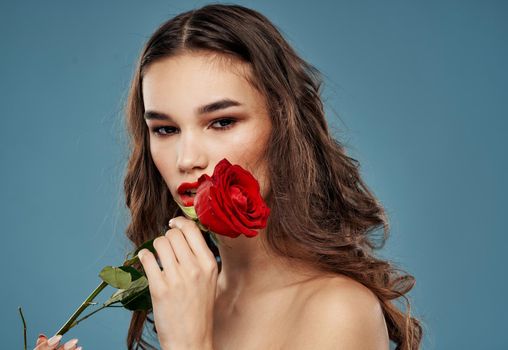 Woman with a rose in her teeth evening makeup blue background model. High quality photo