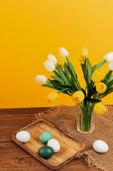 bouquet of flowers in a vase easter eggs decoration holiday yellow background. High quality photo