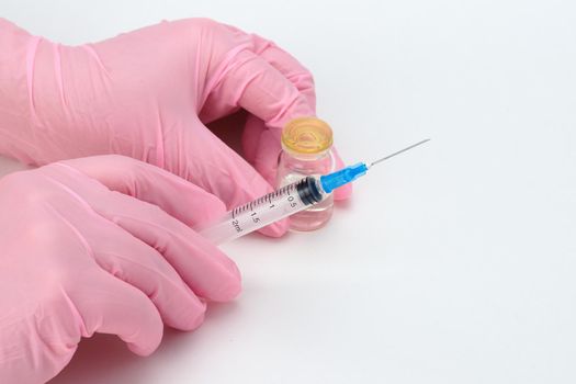 A doctor in medical gloves holds a syringe and a vial with a vaccine or drug in his hands. High quality photo