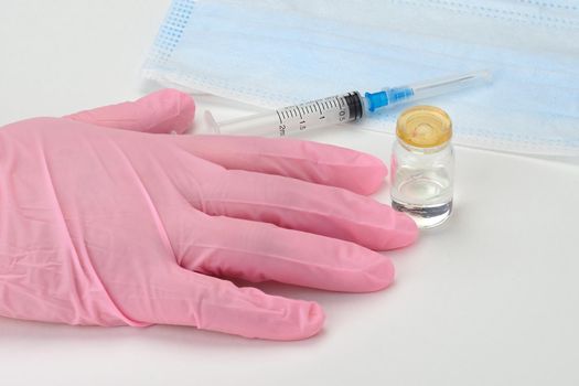 A doctor in medical gloves holds a syringe and a vial with a vaccine or drug in his hands. High quality photo