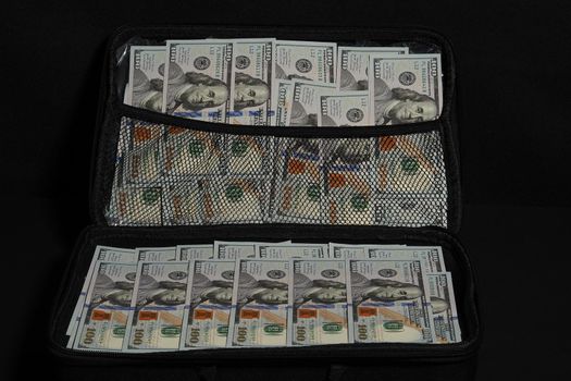 Packs of money in a suitcase. The American dollar, a hundred dollars banknote on a black background. High quality photo