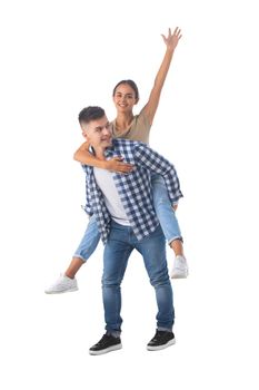 Young happy couple with her at piggyback ride isolated on white background, casual people