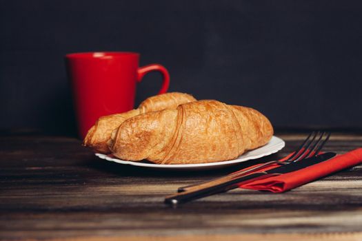 fresh croissant on a plate kitchen utensils coffee cup breakfast. High quality photo