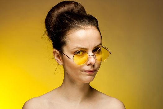 woman with bare shoulders yellow glasses collected hair emotions. High quality photo