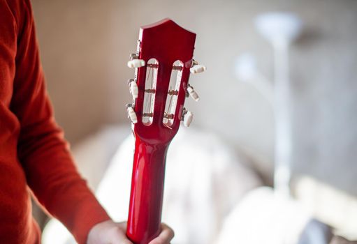 Close-up of a guitar player or a person learning to play an acoustic guitar. Home learning to play a musical instrument