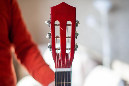 Close-up of a guitar player or a person learning to play an acoustic guitar. Home learning to play a musical instrument