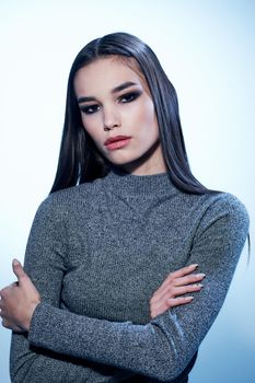 Beautiful woman in a gray sweater gestures with her hands and makeup with eyeshadow on her eyelids. High quality photo