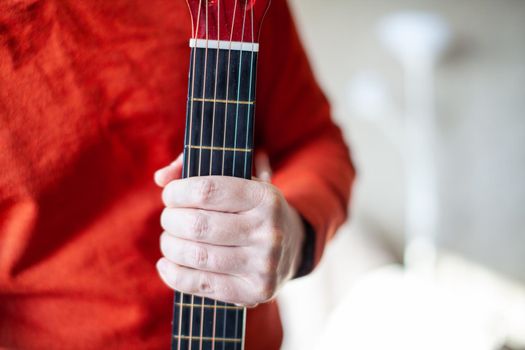 Close-up of a guitar player or a person learning to play an acoustic guitar. Home learning to play a musical instrument