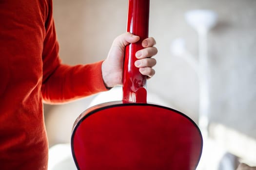 Close-up of a guitar player or a person learning to play an acoustic guitar. Home learning to play a musical instrument