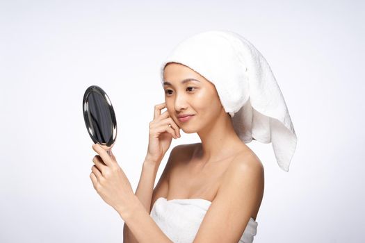 pretty woman with a towel on her head looks in the mirror skin care after shower. High quality photo