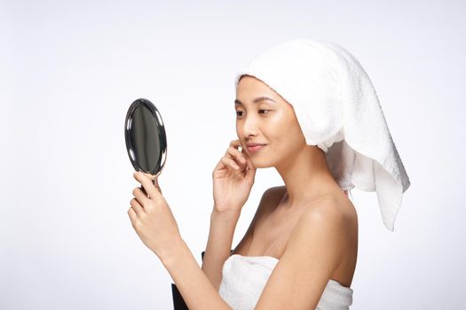 pretty woman with a towel on her head looks in the mirror skin care after shower. High quality photo