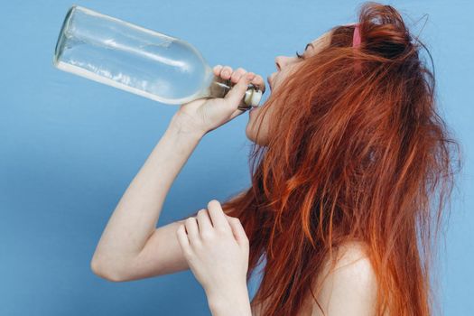 drunk woman with bottle of alcohol emotions blue background. High quality photo