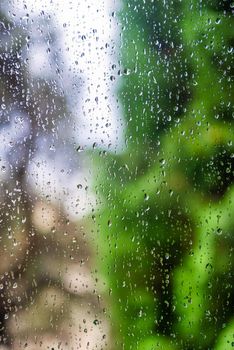 Water drops on window glass with blur garden background