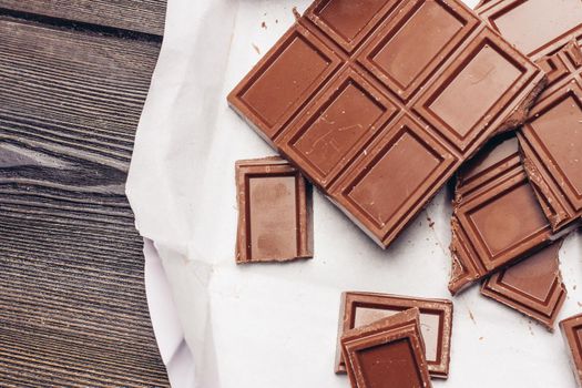 chocolate cubes broken on brown paper on the table. High quality photo