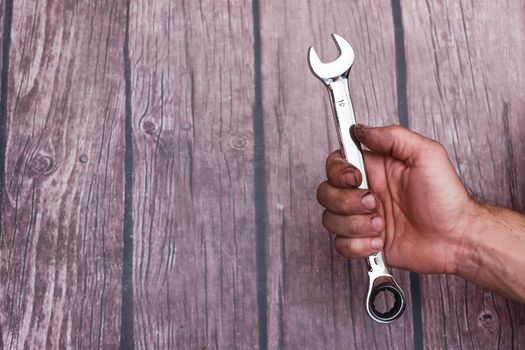 worker's hand with a chrome-plated wrench. The spanner mirrors like a mirror.