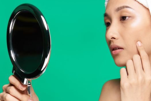 pretty woman mirror on her hands clean skin face close up green background. High quality photo