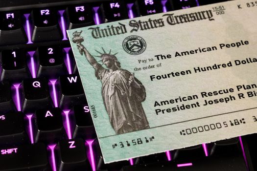 US Treasury concept check to illustrate coronavirus stimulus payment on keyboard used for working from home