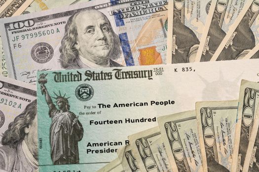 Stack of 20 dollar bills with US Treasury illustrative check to illustrate American Rescue Plan Act of 2021 payment on cash background