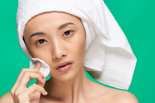 pretty asian woman bare shoulders towel on head cotton pad clean skin green background. High quality photo