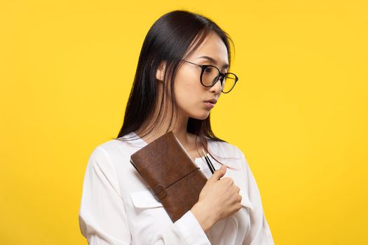 Business woman with glasses notepad in the hands of manager office yellow background. High quality photo
