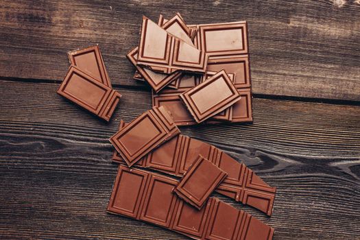 bar of chocolate broken into cubes on a wooden table. High quality photo