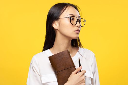 Business woman in glasses holding notepad in hands official yellow isolated background. High quality photo