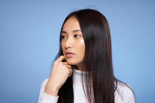 brunette asian touching face with hand makeup model white sweater. High quality photo