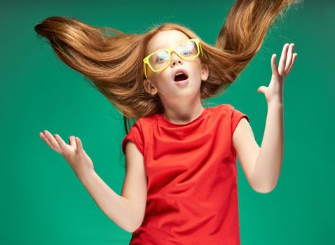 girl in a red T-shirt with loose hair emotions yellow glasses Green background. High quality photo