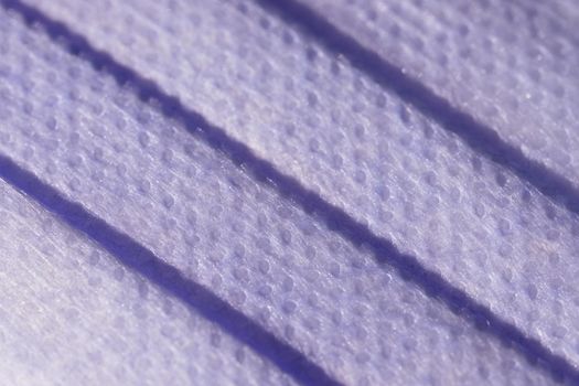 Super macro image showing the surface texture of a 3 ply single use face mask. Medical mask with 3 folds, splash proof and filtering ability.