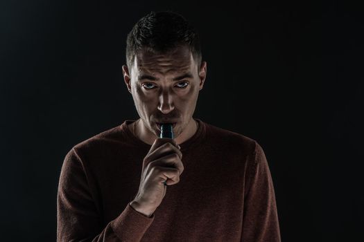 a man smokes a vape on a black background white smoke steam portrait close-up. High quality photo