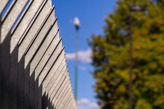 Close-up of the top of a black metal fence against the blue sky on a sunny day