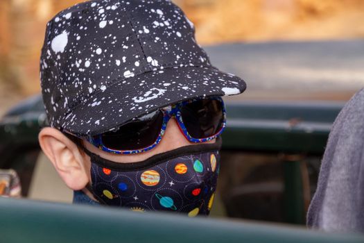 Portrait of a cute boy wearing a cap, face mask and sunglasses