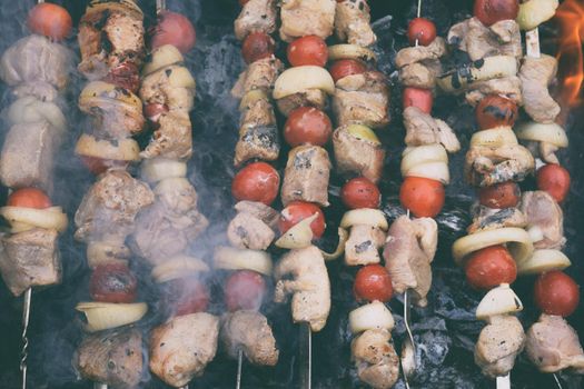 Grilled kebab cooking on metal skewers grill . Roasted meat cooked at barbecue with smoke. Traditional eastern dish, shish kebab. Grill on charcoal and flame, picnic, street food.