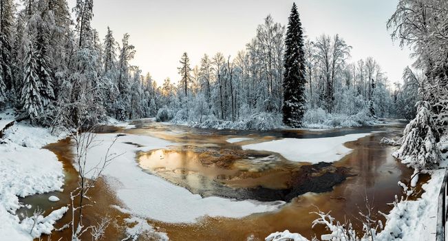 The wild nature at sunset, the wild frozen small river in the winter wood, the Red River, ice, snow-covered trees. High quality photo