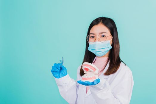 Asian beautiful woman dentist holding silicone orthodontic retainers and model teeth denture isolated on blue background, Teeth retaining tools after removable braces, Orthodontics dental healthy care