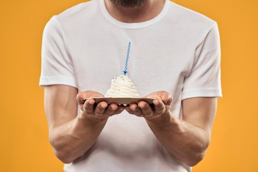 A man with a birthday cake in his hands on a yellow background birthday dessert. High quality photo