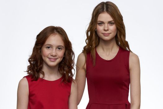 Mom and daughter stand side by side and fun family joy light background. High quality photo