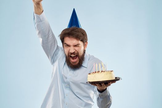 cake in a plate and birthday man with a cap on his head blue backgroun. High quality photo