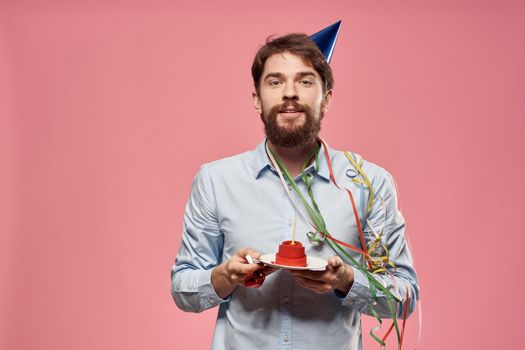 Bearded man with cake on pink background birthday party corporate emotions model loneliness. High quality photo