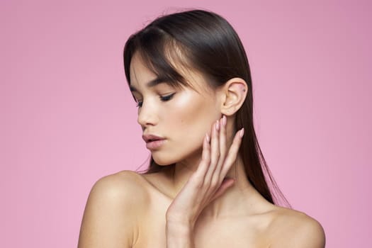 brunette bare shoulders clear skin body care pink background. High quality photo