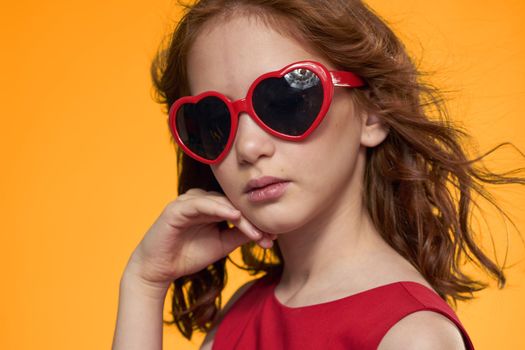 Girl in black glasses red dress childhood fun yellow background. High quality photo