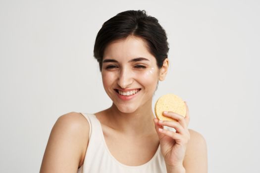 Cheerful pretty woman with a sponge in her hands skin care cosmetics color background light background. High quality photo